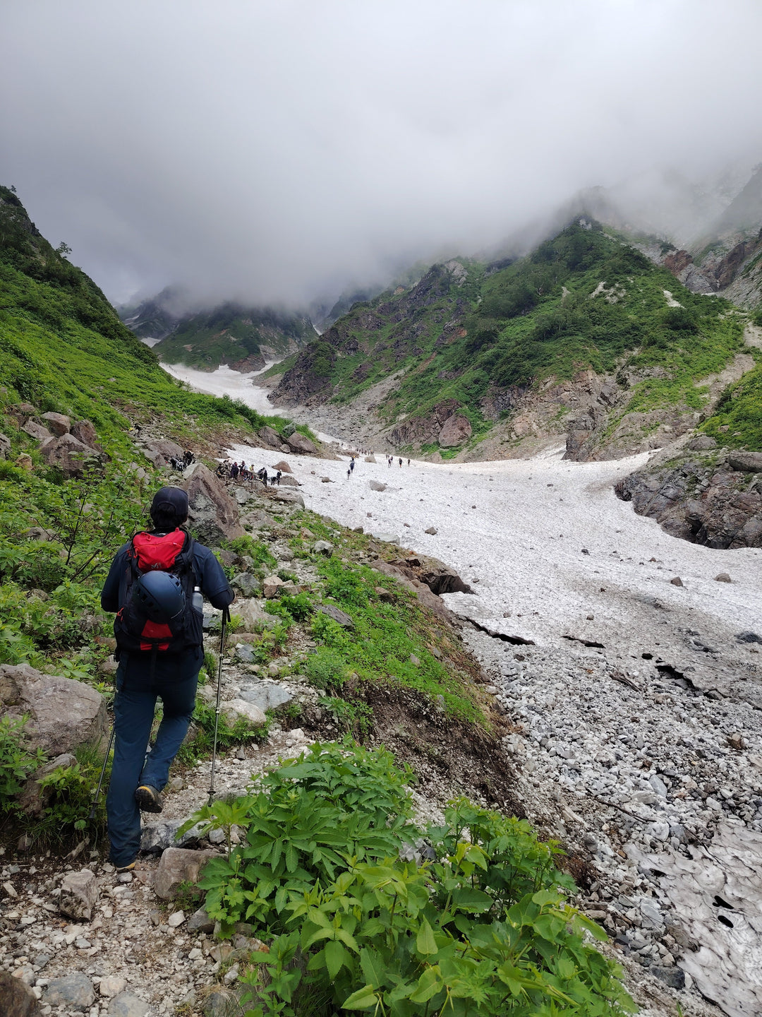 Hiker approaching the Hakuba Daisekkei snow valley in the Northern Japan Alps in July