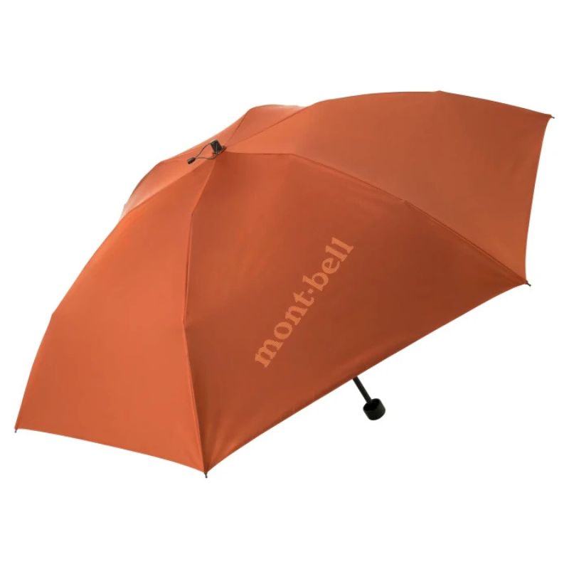 A folded orange Montbell umbrella with a compact design, featuring a branded label when opened.