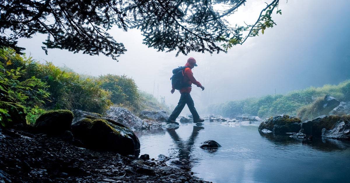 Hiker crossing a mountain stream in Montbell gear