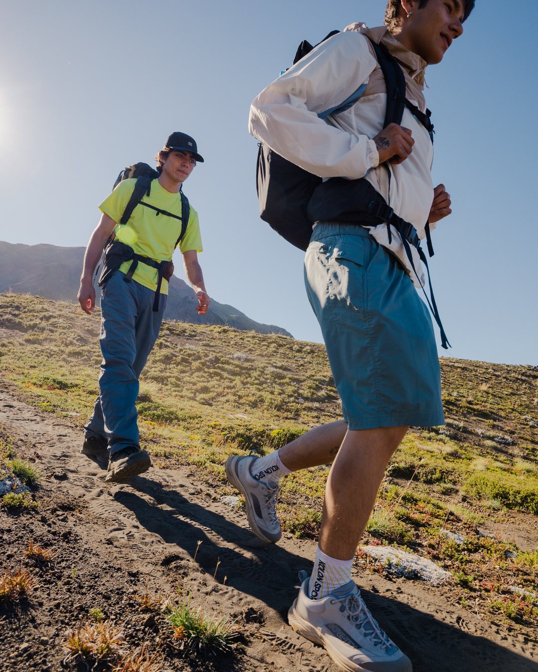 Two hikers in Kolon Sport outdoor wear walking up a grassy mountain trail
