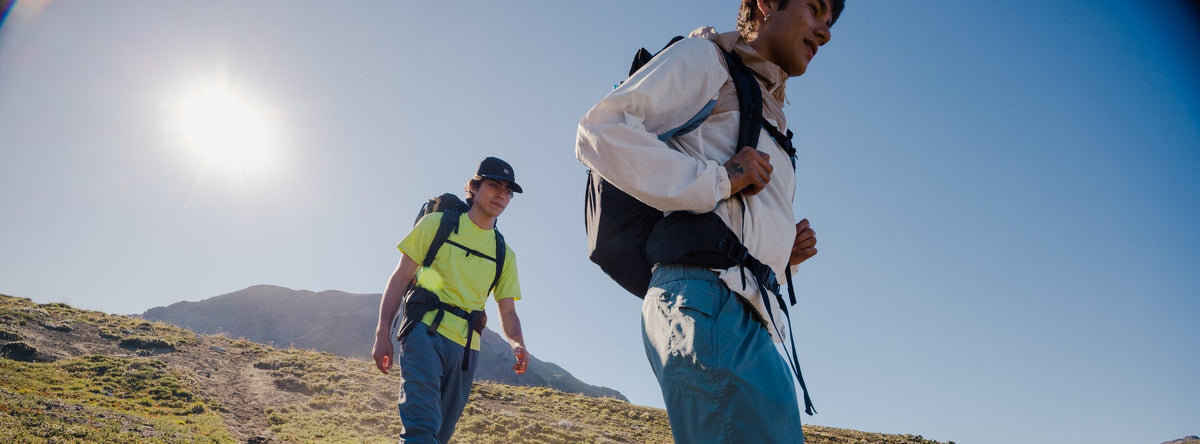 Two hikers in Kolon Sport outdoor wear walking up a grassy mountain trail
