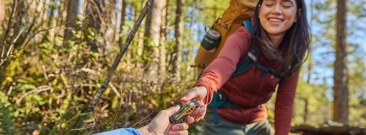 Hiker in a forest handing over a Leatherman multi-tool