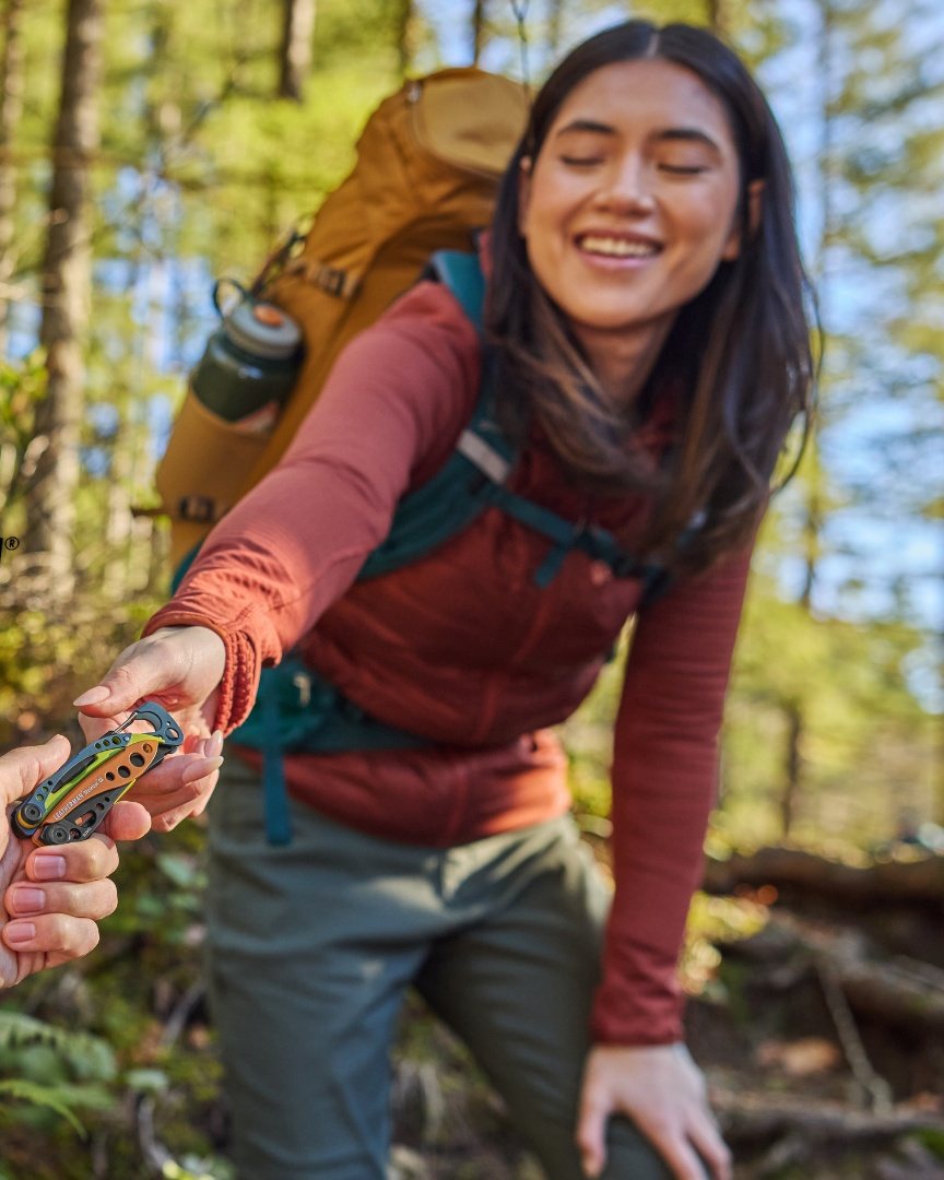 Hiker in a forest handing over a Leatherman multi-tool